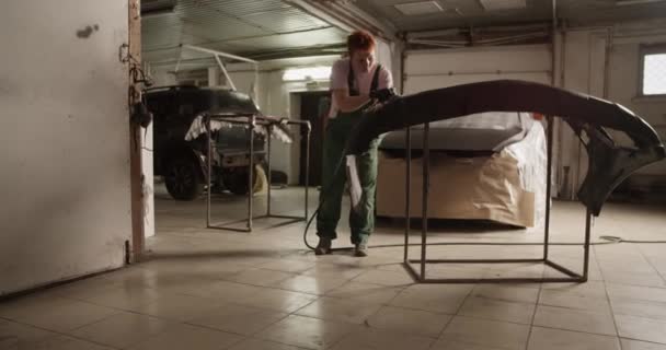 ガレージでの作業中に塗装車のバンパーをバッファリング均一で全身職人の女性のハンドヘルドショット — ストック動画