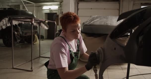 专业车间工作时 用砂磨机从汽车保险杠上移除了旧油漆的姜女机修工手持枪法 — 图库视频影像