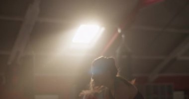 Güneşli spor salonunda boks antrenmanı sırasında pencereye yumruk atan enerjik kadın boksörün düşük açılı el kamerası görüntüsü.
