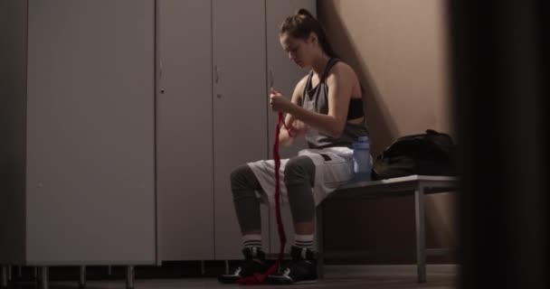 Spor Salonunun Soyunma Odasında Bankta Otururken Kamerasıyla Kadının Bandajı Elinden — Stok video