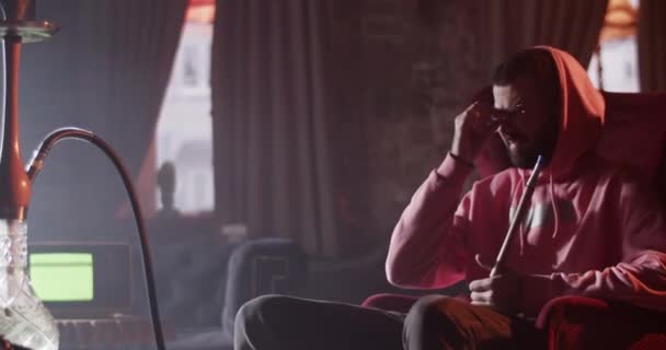 Ung Mand Hættetrøje Sidder Lænestol Med Vandpibe Tager Briller Mens – Stock-video