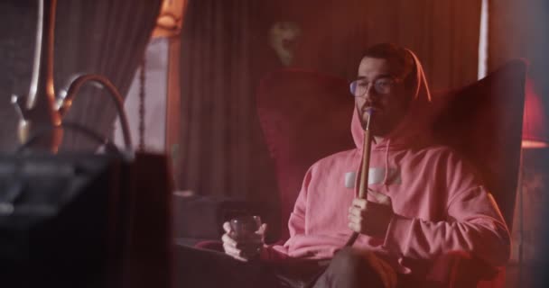 Millennial Man Hoodie Exhaling Hookah Smoke While Chilling Drink Glass — Stock video