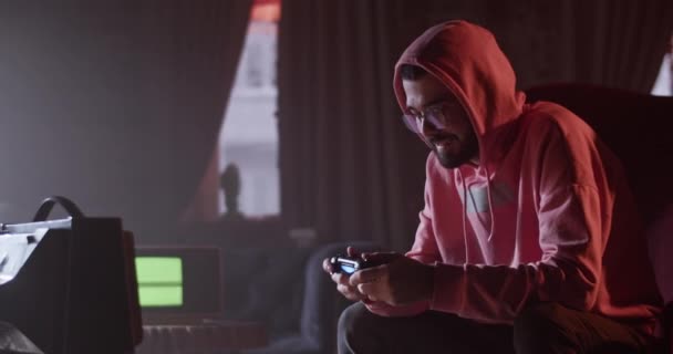 Focused Young Bearded Man Hoodie Glasses Sitting Small Playing Videogame — Stockvideo