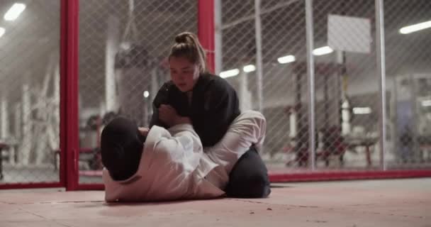 Muslim Female Fighter Performing Triangle Choke While Lying Floor Fighting — Stockvideo