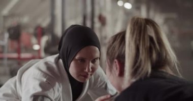 Handheld shot of Muslim fighter touching opponent while sparring during BJJ training in gym