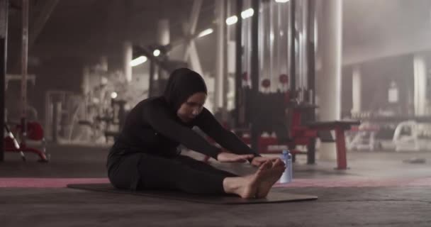 Barefoot Muslim Female Athlete Touching Feet Stretching While Doing Seated — Stockvideo