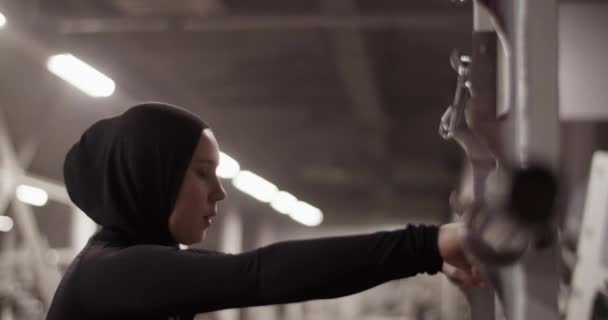 在体操训练中 穆斯林女运动员戴头巾把杠铃挂在肩上的手持跟踪照片 — 图库视频影像