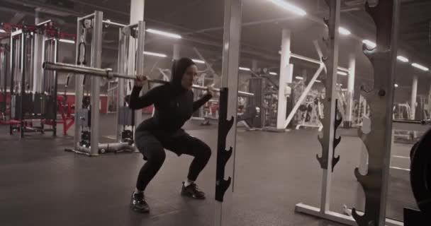 在健身房进行健身训练时 穆斯林女运动员将杠铃架在肩上 蹲伏在地的手持照片 — 图库视频影像