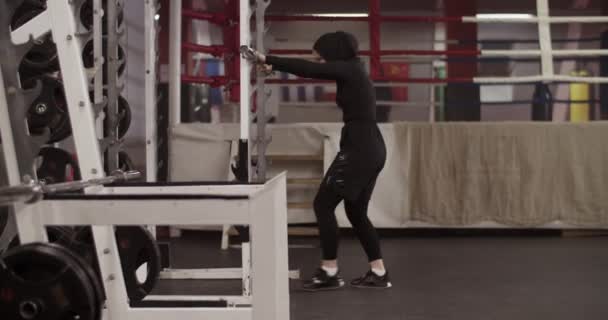 体育館でのフィットネストレーニング中に肩にラックからベルを入れて不法占拠イスラム教徒のスポーツ女性のハンドヘルドショット — ストック動画