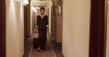 İş gezisinden sonra otel koridorunda bavulla dolaşan, resmi giyinmiş, kendine güvenen zarif bir Afro-Amerikan bayan yönetici.