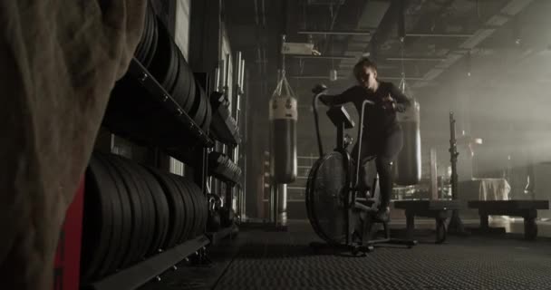 在现代体操训练中 体格健壮 体格健壮 一头长发 身强体壮的年轻女运动员在空中自行车上锻炼 并检查健身跟踪器的全长 — 图库视频影像