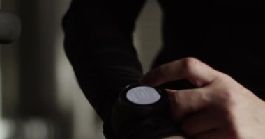 Aktif giyimli, uzun siyah saçlı genç ve bitkin bayan sporcu spor salonundaki sıkı antrenmandan sonra nabzını kontrol ediyor ve nefes alıyor.