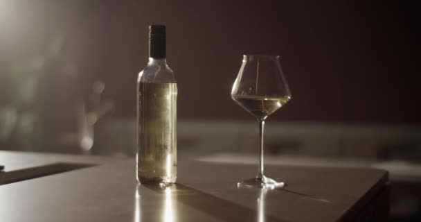 日照时 将白色酒瓶置于酒吧台上的泛右手照 酒吧台上有雅致的酒杯 背景模糊 — 图库视频影像