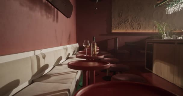 ソファとカウンターの近くの小さな赤いテーブルの上に白ワインボトルとガラスとモダンなバーのリアルタイムインテリアデザイン太陽の光の下で — ストック動画