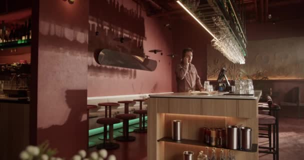 即时手持照片拍摄到年轻的男性酒吧间店主站在柜台前与客户通话 与他们共进晚餐 — 图库视频影像