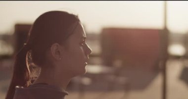 Kendine güvenen kapüşonlu kadının etrafında dön. Güneşli şehirde yoğun bir eğitimden sonra derin bir nefes al ve dinlen.