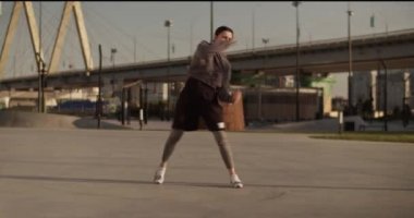 Tam vücut pozu. Kendine güvenen ve kapüşonlu güçlü sporcu kadın. Boş şehirde sabah antrenmanında gölgelerde boks yaparken hızlı bir şekilde hava alıyor.