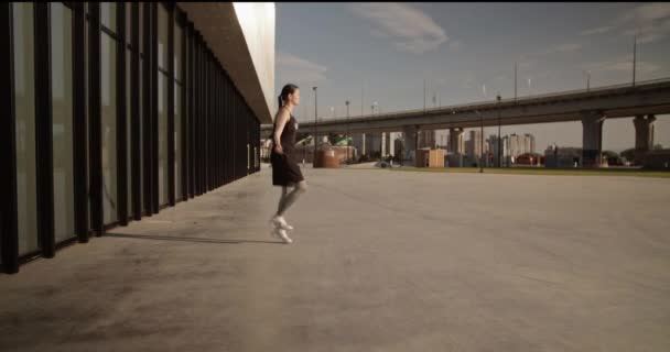 サイドビュー現代的な街並みでアスファルトの地面に心臓暖かくジャンプロープを行うアクティブウェアで焦点を当てた運動女性のフルボディ — ストック動画