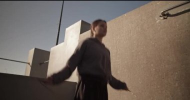 Sabahları çatıda yoğun idman yaparken spor kıyafetli genç bayan sporcunun aşağı eğilme sahnesi.