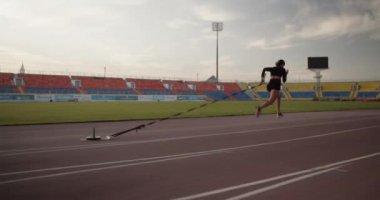 Koşu antrenmanı sırasında spor giyim sektöründe ağır toplarla koşan kararlı genç bir kadının gerçek zamanlı görüntüsü.