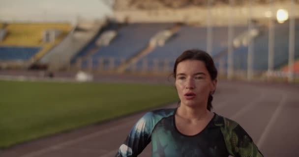 朝の陸上トレーニングの後 陸上競技場を歩く若い疲れと汗をかいた女性のシュプリンターのリアルタイム追跡ショット — ストック動画
