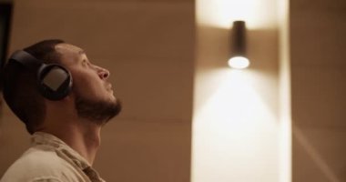 Kulaklık takan, kollarını oynatan ve geceleri dans eden modern çağdan kalma bir adamın el kamerası görüntüsü.