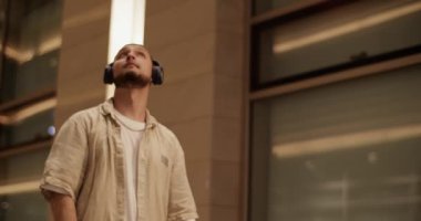 Modern binaların karşısında dans ederken kulaklıklı modern dansçının el kamerasıyla çekilmiş fotoğrafı.