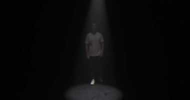 Genç duyarlı erkek dansçının kulaklık takıp karanlık stüdyoda güncel koreografiyi dinlerken elleri ile spot ışıklarını kapattığı sahneyi yakınlaştır.