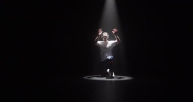 Gerçek zamanlı olarak genç, enerjik, beyaz erkek dansçının kulaklıkla müzik dinlerken, Down-Rock hareketleri yapıp, spot ışıklarıyla spot ışıklarıyla break dans yaptığı sahneyi yakınlaştır.