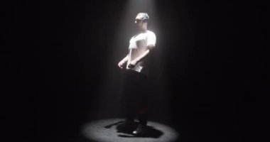 Kulaklıklı modern beyaz adamın gerçek zamanlı vücut çekimi. Kolları ışığın altında dans ediyor.