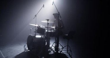 Erkek davulcu bas bas pedalına tıklıyor ve bilgisayar ve mikrofonla sahnede çalarken profesyonel davul setinde çalıyor.