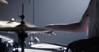 Gece kulübündeki rock konserinde sahnede davul çalarken beyaz kıyafetli isimsiz bir erkek davulcunun yan görüntüsü 