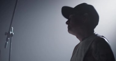 Siyah arkaplana karşı davul çalarken, davul çalarak şapkalı genç ve ilham verici erkek davulcunun