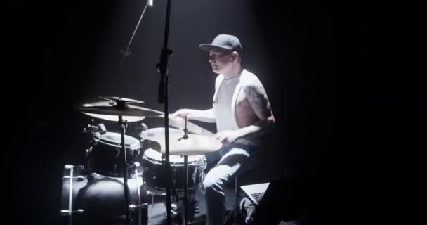 穿着休闲装头戴便帽坐在凳子上 手握木棍在鼓上演唱的天才年轻纹身男摇滚歌手的侧貌 — 图库视频影像