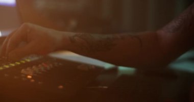 Koyu renk kayıt stüdyosundaki karıştırıcı panelinde kayan erkek müzisyenlerin oluşturulan şarkı ve kafa sallamalarını dinlerken yan görünümü