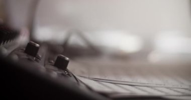 Kayıt stüdyosundaki müzik notalarının yakınındaki gitar amplifikatörüne enstrüman kablosu takan tanınmayan müzik bestecisinin yakın çekimi