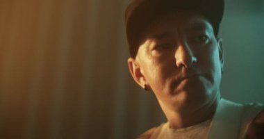 Erkek rock gitaristi, yapım stüdyosunda şarkı kaydederken, karanlık kontrol odasında elektro gitarda melodi çalıp kafa sallıyor.