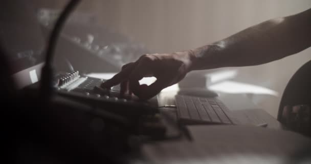 オーディオミキサーのノブを調整し 薄暗い光の中で音楽スタジオで働いている間ベースギターを演奏する匿名のサウンドプロデューサーのリアルタイム — ストック動画