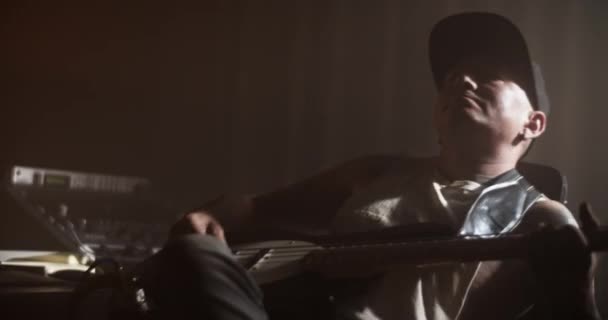 Erkek Müzisyenin Karanlık Kayıt Stüdyosunda Sandalyede Oturup Bas Gitar Çalarken — Stok video