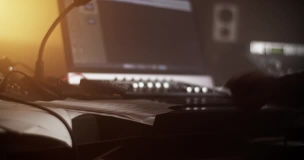 男声制作人在录音室靠近混音器和计算机工作时翻阅乐谱的侧视图 — 图库视频影像