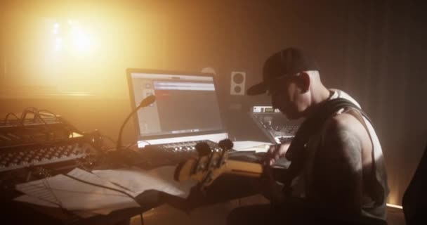 Kézi Felvétel Ihletett Férfi Művész Sapkában Játszik Basszusgitár Asztalnál Miközben — Stock videók