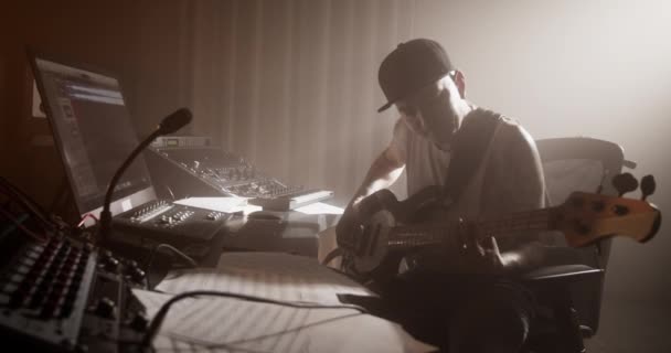 직장에서 장비를 테이블에 앉아서 창조적 베이스 기타를 연주하는 사운드 프로듀서의 — 비디오