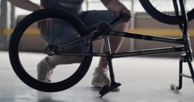 BMX 'in arka tekerlerini baş aşağı yerleştirirken, sırtüstü oturan ve bisiklet pedallarını çeviren isimsiz bir adamın gerçek zamanlı el kamerası görüntüsü.