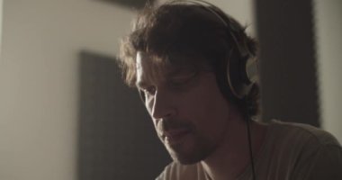 Evde müzik bestelerken ve prova yaparken kulaklık takan yaratıcı yetişkin erkeklerin düşük açısı.