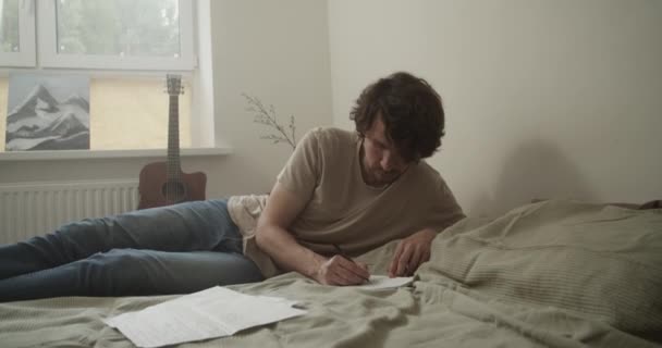 Odaklanmış Erkek Şarkı Yazarının Gerçek Zamanlı Resmi Yumuşak Yatakta Yatar — Stok video