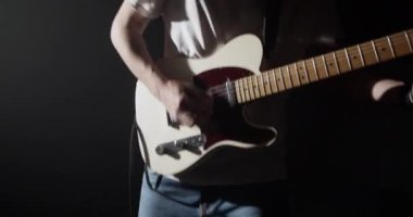 Karanlıkta spot ışığı altında dikilirken elektro gitar çalan adamın sağa dön