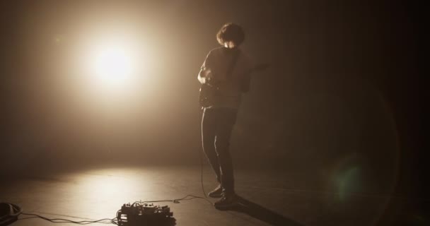 노란색 스포트라이트에 대하여 어두운 방에서 기타를 활기차게 연주하면서 음악을 수행하는 — 비디오