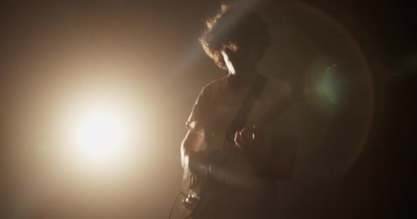 千年男吉他手在黑暗俱乐部表演时摇头的实时低角在黄色聚光灯下弹奏电吉他 — 图库视频影像