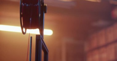 3D yazıcının gerçek saatini plastik iplikli filament makara ile eğerek prototip oluştururken, erkek ana atölyede profesyonel atölyede netbook kullanıyor.