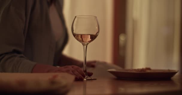 暗いアパートでガールフレンドと話しながら プレート付きのテーブルに座って白ワインを飲んだ匿名の女性のソフトフォーカスリアルタイム — ストック動画